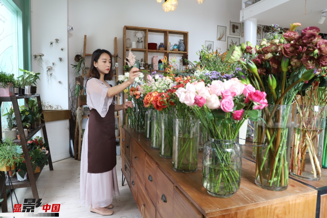 王黎媛是一名河南姑娘，在昆明念完大學(xué)后，就再也舍不下春城的藍(lán)天陽光、青山碧水，更舍不下這里的四時繁花，于是就干脆留了下來，成了一名媒體人。2017年的時候又毅然辭去工作，創(chuàng)業(yè)開起了花店，成了都市里的一名“花房姑娘”。圖為王黎媛在自己的花店中整理鮮花。新華網(wǎng) 周亞平/攝 念新洪/文